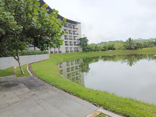 Obraz premium Serene Lakeside View with Modern Building and Greenery