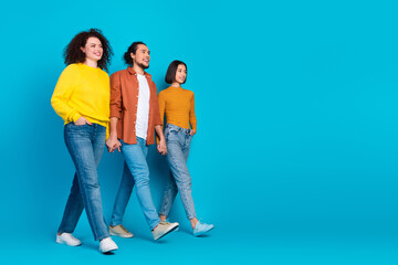 Fototapeta premium Three friends in casual fashion walking together against a vibrant blue background, showing happiness and diversity in style