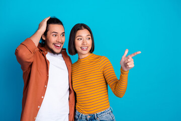 Happy friends pointing and sharing excitement against a vibrant blue backdrop in a casual and...