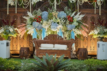 Elegant Wooden Wedding Stage Decor with Lush Floral Arrangements and Intricate Carvings