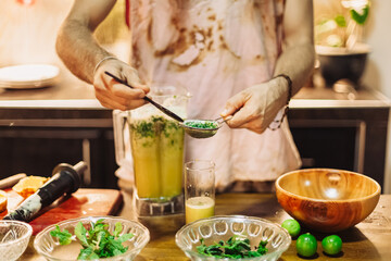Making fresh mango-lime juice with mint in a blender. Vegan smoothie prep in a bright tropical kitchen. Healthy, plant-based, and eco-friendly cooking lifestyle