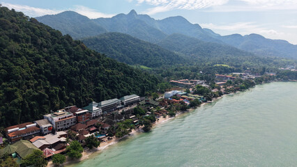 Breathtaking aerial view of koh chang's coastline, where vibrant hotels and resorts meet the edge of a lush, untouched rainforest, creating a stunning contrast between nature and development