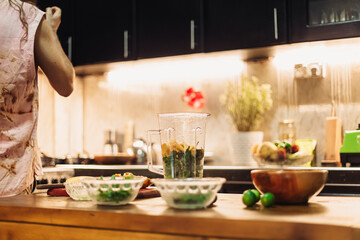 Making fresh mango-lime juice with mint in a blender. Vegan smoothie prep in a bright tropical kitchen. Healthy, plant-based, and eco-friendly cooking lifestyle