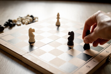 Hand is moving chess piece on chessboard. Game concept