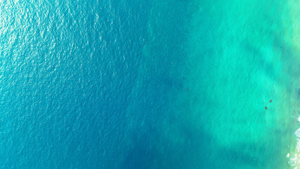 Aerial view of crystal clear turquoise water gently sloping from deep blue to vibrant aquamarine, showcasing a breathtaking gradient in a tropical ocean paradise