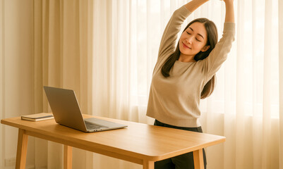 Young woman takes a refreshing stretch break at her home desk with a laptop, embracing healthy work habits, physical wellness, and a balanced routine—bathed in soft natural light and peaceful energy

