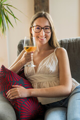A smiling young woman drinking wine in available light