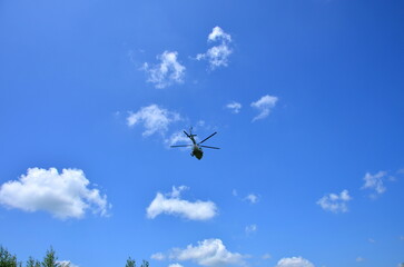 low flying helicopter in the sky with clouds on a summer day