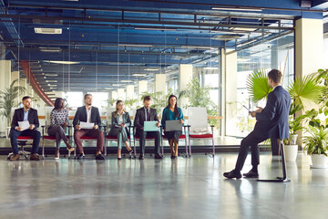 Businessman conducting a meeting or presentation for a team of business people in an office. He is actively talking with colleagues about work related matters. Communication in a professional setting.