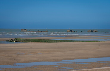 Asnelles-Sur-Mer, France - 05 16 2025:  View of the sandy beach, sea and pontoons from the beach .