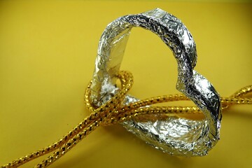 Srebrne serce na żółtym tle, przeplecione żółtymi sznurkami © tomo81