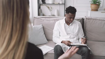 Doctor appointment, adult woman consulting with health professional in clinic. Cosmetic surgery for stay beautiful and health in middle-age, blonde lady talking with young african man in white gown - Powered by Adobe