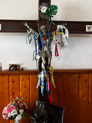 Jesus sculpture on a cross in chapel along the St. James way in Arao, Portugal, with added objects from pilgrims, for good luck, protection in form of a religious offering
