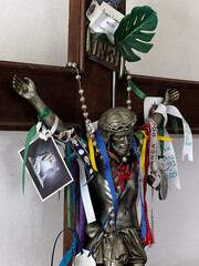 Jesus sculpture on a cross  in chapel along the St. James way in Arao, Portugal, with added objects from pilgrims, for good luck, protection in form of a religious offering