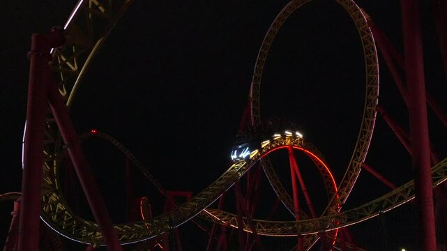 Rollercoaster Night Ride Loop Amusement Park: Thrilling nighttime rollercoaster loop ride at an amusement park, showcasing exhilarating speed and dynamic lighting.