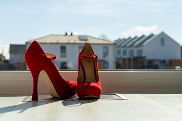 Red ladies pumps on the floor in front of a window