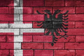 colourful painted big national flag of albania and flag of denmark on a massive old brick wall background. concept