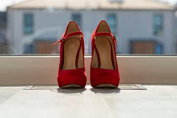 Red ladies pumps on the floor in front of a window
