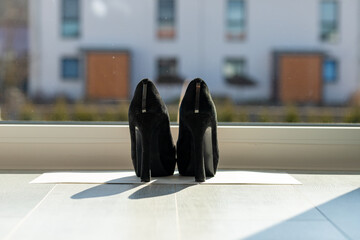 Black ladies pumps on the floor in front of a window