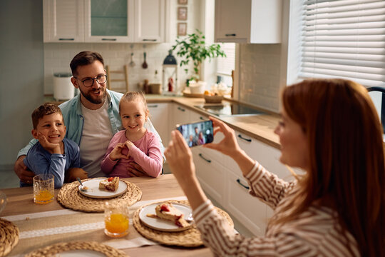 Happy family being photographed while having dessert at dining table.