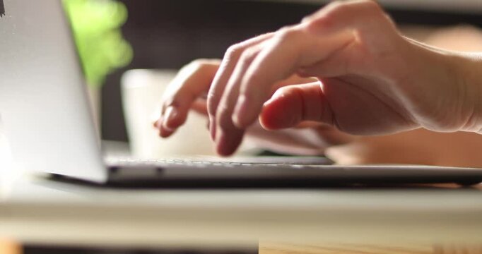 Hand of woman using laptop computer to work, typing at home and scrolling, while sitting on table workplace at night, Close-up of young women hand	
