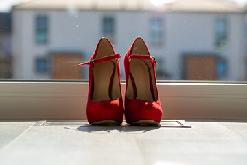 Red ladies pumps on the floor in front of a window