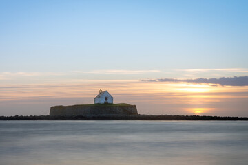 Obraz premium St Cwyfan's Church in the Sea, Anglesey, Wales, at Sunset