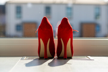 Red ladies pumps on the floor in front of a window