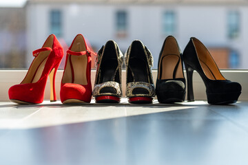 3 pairs of women's pumps in a row on the floor in front of a window