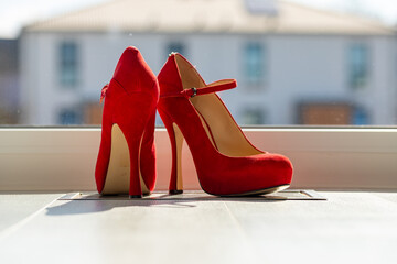 Red ladies pumps on the floor in front of a window