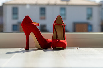 Red ladies pumps on the floor in front of a window