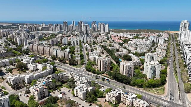 Aerial drone view of Netanya, a coastal city in central Israel. The scene showcases residential buildings, the Mediterranean Sea, cliffs, and urban development along the shoreline.