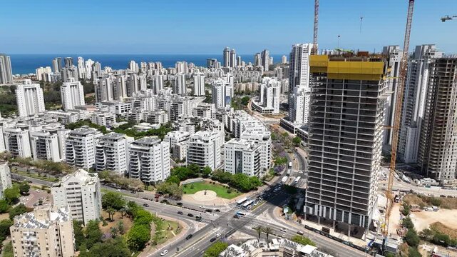 Aerial drone view of Netanya, a coastal city in central Israel. The scene showcases residential buildings, the Mediterranean Sea, cliffs, and urban development along the shoreline.