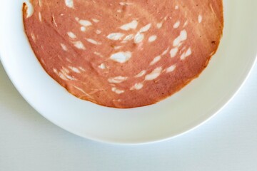 Close-up of a sliced bologna on a white plate