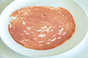 Close-up of a sliced bologna on a white plate