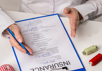 Signing Insurance Document with Blue Pen on Desk in Office