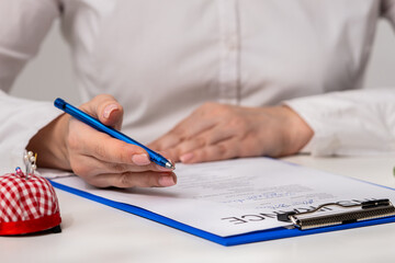 Woman Writing on a Document with Blue Pen on Desk