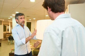 Interior designer showing lamp to client in furniture showroom