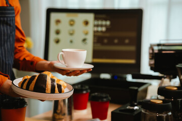 Barista in coffee shop preparing espresso drinks, working with coffee machine in a comfortable indoor atmosphere, representing small business and service.
