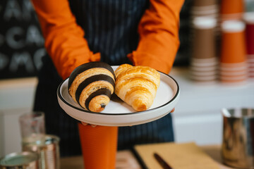 Barista in coffee shop preparing espresso drinks, working with coffee machine in a comfortable indoor atmosphere, representing small business and service.