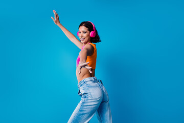 Stylish young woman posing confidently wearing colorful casual attire and headphones against a...