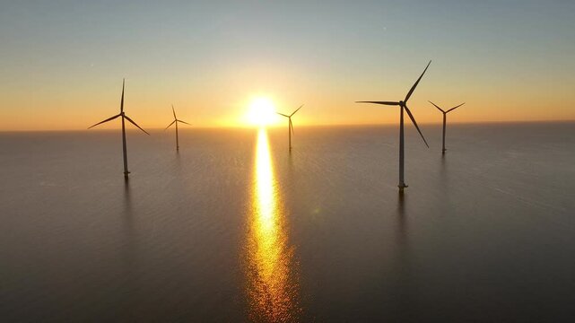 Offshore wind farm in the sea at sunrise or sunset. Aerial view of Windpark with wind turbines, windmills in Netherlands. Power plant, climate change, sustainable resources, green renewable energy. 4K