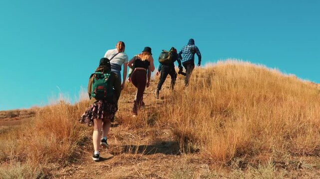 Multicultural group hiking on remote trail in golden hills, facing physical challenge and bonding through powerful outdoor desert journey. Bottom view.