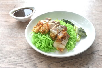Chinese jade noodles topping roasted crispy pork dipping sweet soy sauce on plate 