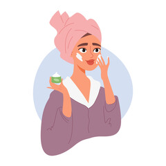Woman with towel on head applies cream to her face. Beauty treatment and self-care concept