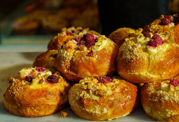 Golden sweet buns stacked with sugar, berries, and soft cheese.