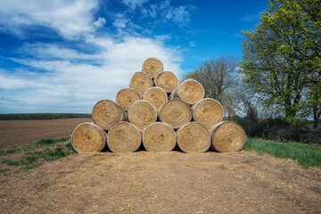 Amazing view with a large pile of bales of hay and blue sky with fluffy white clouds