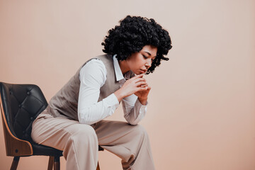 Young female professional in formal attire contemplating with focus in a modern chair against a...