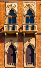 Close-up view of a historic building facade in Italy, showcasing its detailed stonework and arched...