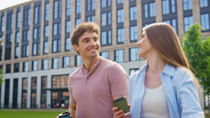 Fototapeta premium Smiling man woman walking together with coffee near office building closeup.